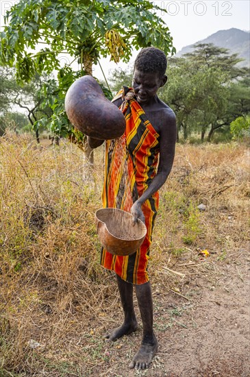 Laarim woman filtering Sorghum in a carabass