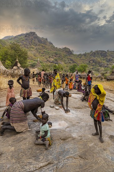 Young girls grinding Sorghum on a rock