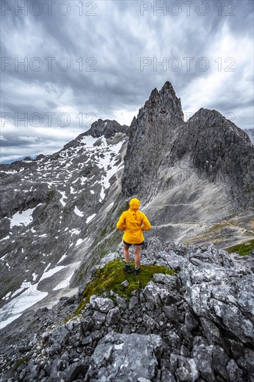 Hiker looking at mountains under dramatic clouds