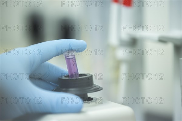 Hand of a medical laboratory assistant holding a reaction vessel in the centrifuge