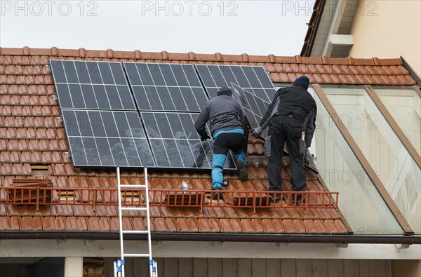 Technicians assembling a photovoltaic system on the roof of a residential building in Markt Swabia