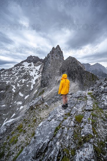 Hiker looking at mountains under dramatic clouds