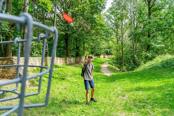 Boy throws a disc at disc golf