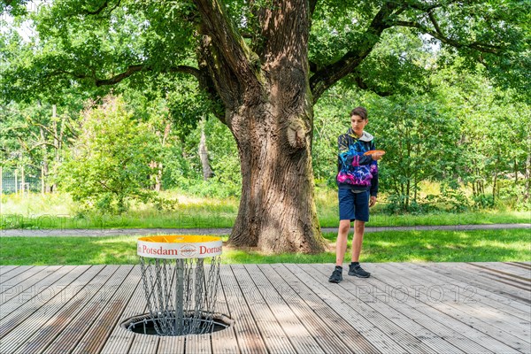 Boy throws a disc at disc golf