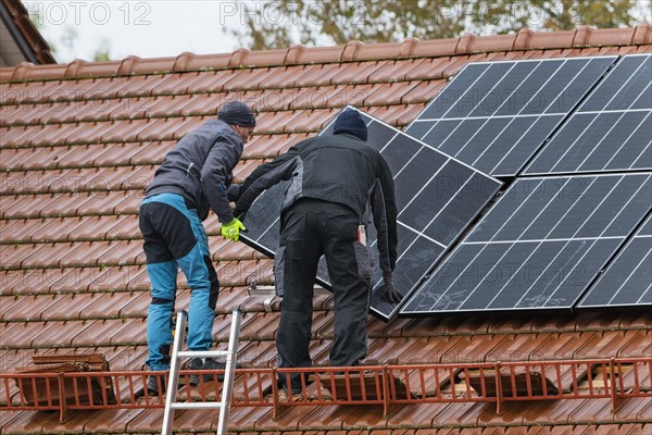 Technicians assembling a photovoltaic system on the roof of a residential building in Markt Swabia