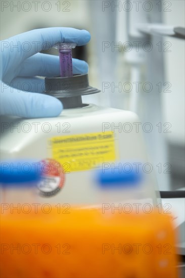 Hand of a medical laboratory assistant holding a reaction vessel in the centrifuge