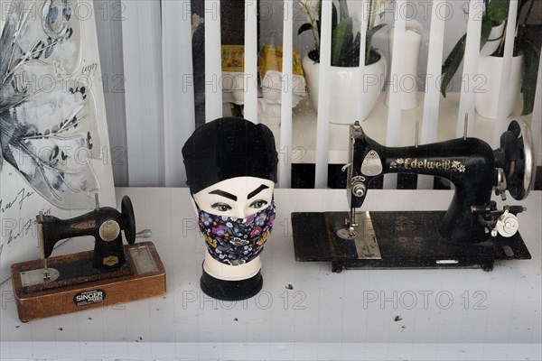 Shop window of a sewing centre with old sewing machines and dead flies in Kempten