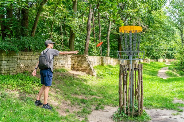 Boy throws a disc at disc golf