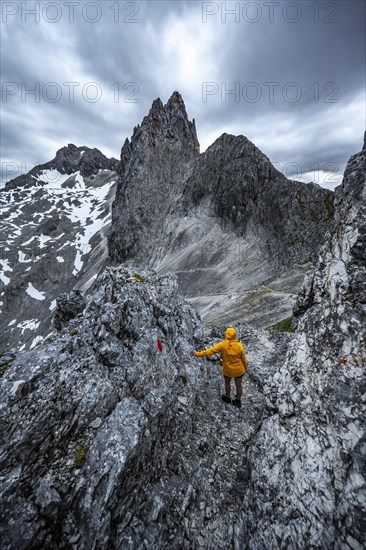 Hiker looking at mountains under dramatic clouds