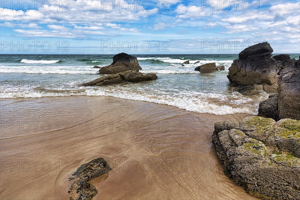 Rocks and surf on sandy beach