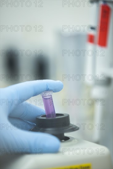 Hand of a medical laboratory assistant holding a reaction vessel in the centrifuge