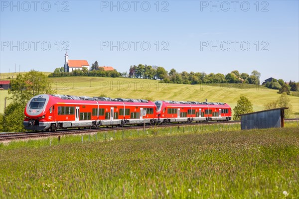 Pesa Link Regional train of Deutsche Bahn DB with church St. Alban in Allgaeu Bavaria in Aitrang