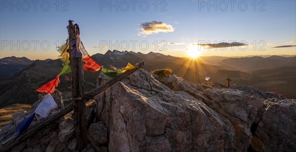 Prayer flags and summit cross on Monte Castellaz at sunset