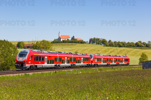 Pesa Link Regional train of Deutsche Bahn DB with church St. Alban in Allgaeu Bavaria in Aitrang