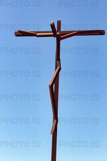 Square corten steel cross against a blue sky