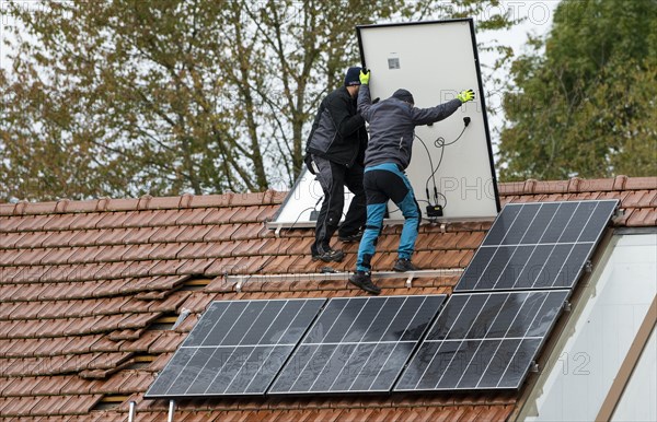 Technicians assembling a photovoltaic system on the roof of a residential building in Markt Swabia