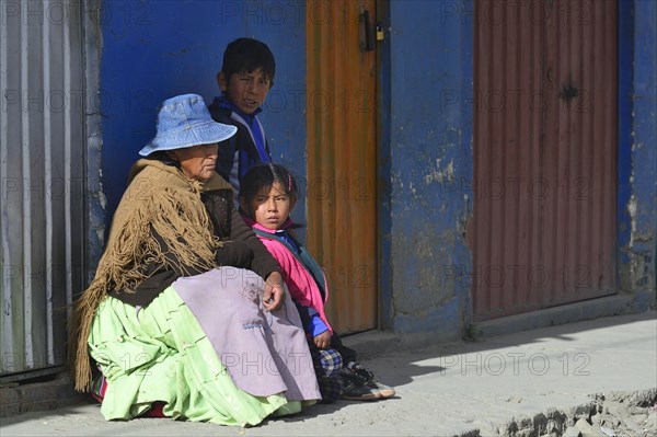 Sitting indigenous woman with two grandchildren