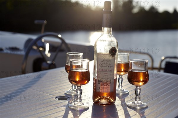 Liqueur with glasses in the backlight on houseboat at the Lot