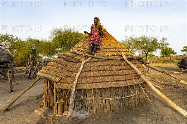 Woman repairing a roof of a traditional build hut of the Toposa tribe