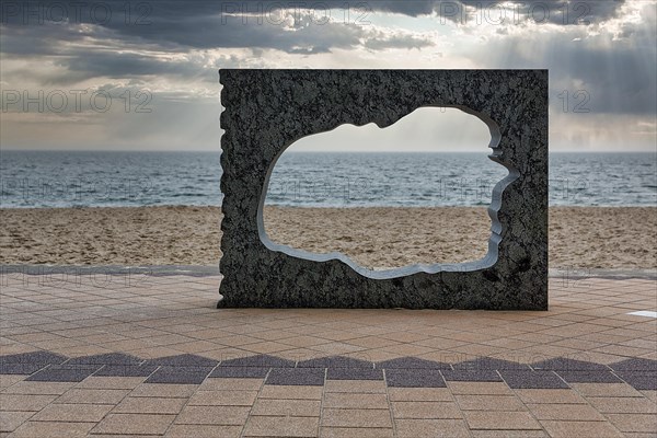 Sculpture in stone with breakthrough in the shape of the island of Foehr and view of the North Sea