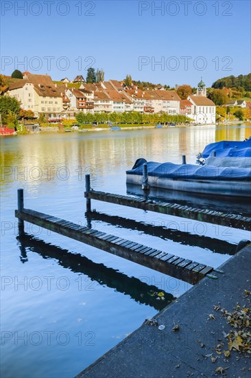 View from the banks of the Rhine over the Rhine towards the old town of Eglisau with reflection on the river water