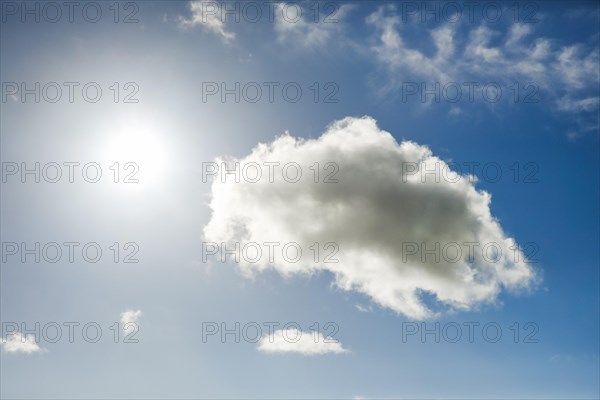 The sun shines next to an cumulus cloud