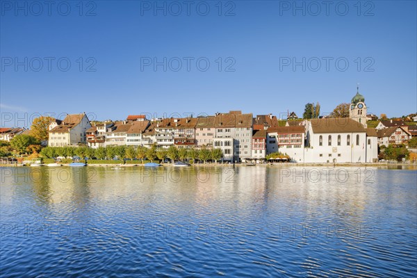 View from the banks of the Rhine over the Rhine towards the old town of Eglisau with reflection on the river water