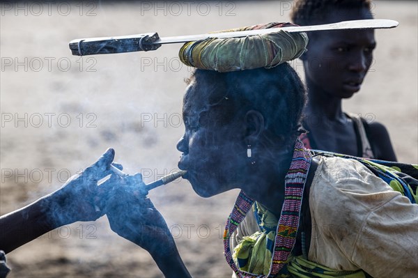 Woman with a machete on her head lightning a cigarette