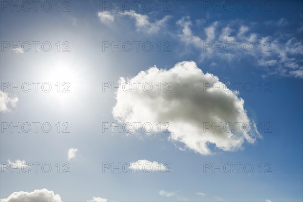 The sun shines next to an cumulus cloud