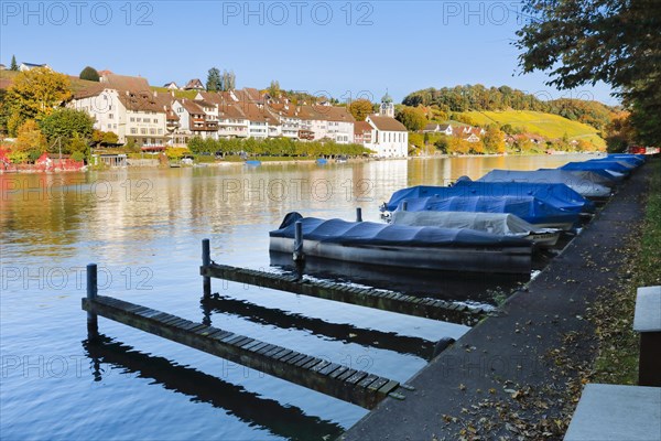 View from the banks of the Rhine over the Rhine towards the old town of Eglisau with reflection on the river water