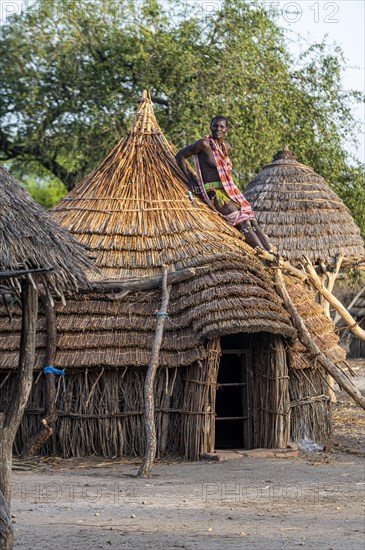 Woman repairing a roof of a traditional build hut of the Toposa tribe