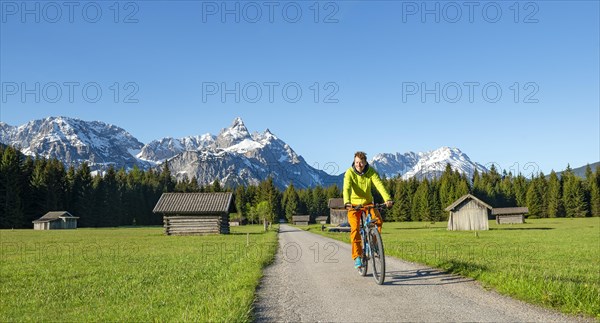 Mountain biker on road through meadow with hay barns