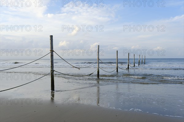 Wooden poles with ropes on the North Sea coast