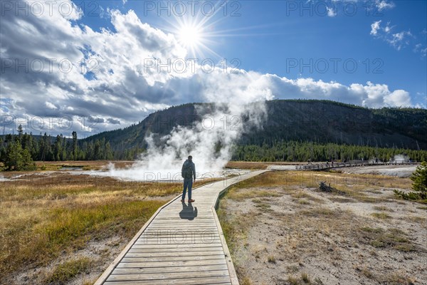 Tourist on a logging road in front of steaming hot spring