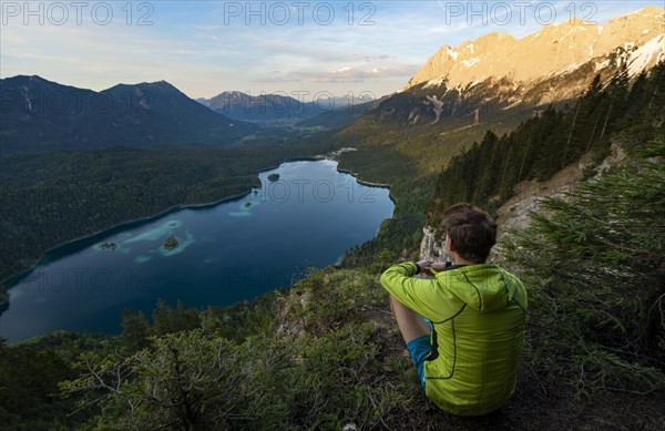 Young man looking over the Eibsee lake at sunset