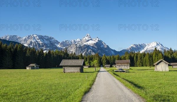 Road through meadow with hay barns