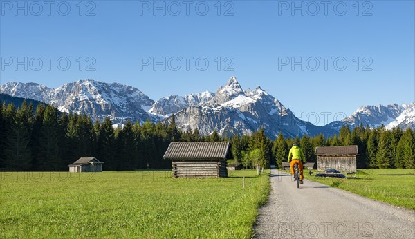 Mountain biker on road through meadow with hay barns