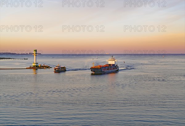 Cargo ship and passenger ferry in the Kiel Fjord at sunset