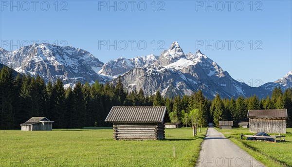 Road through meadow with hay barns