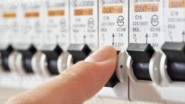 Fuse Box with a finger tripping a circuit breaker