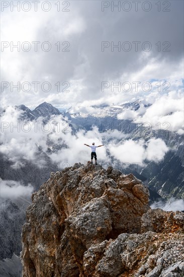 Hiker on a rock stretches arms in the air