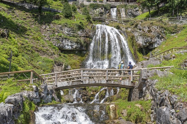 Hikers at the waterfall in front of the Saint Beatus Caves