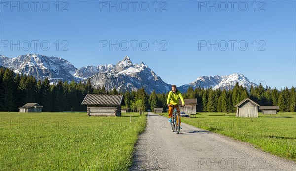 Mountain biker on road through meadow with hay barns