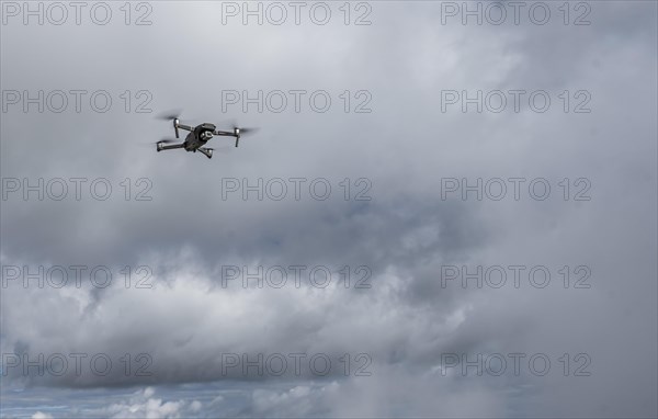 Drone with camera flies in front of clouds