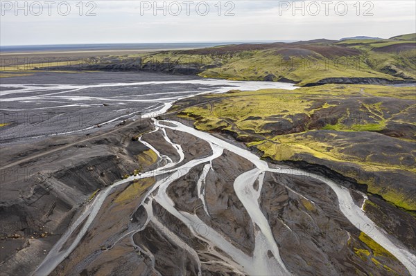 River with fanned out branches through black lava sand