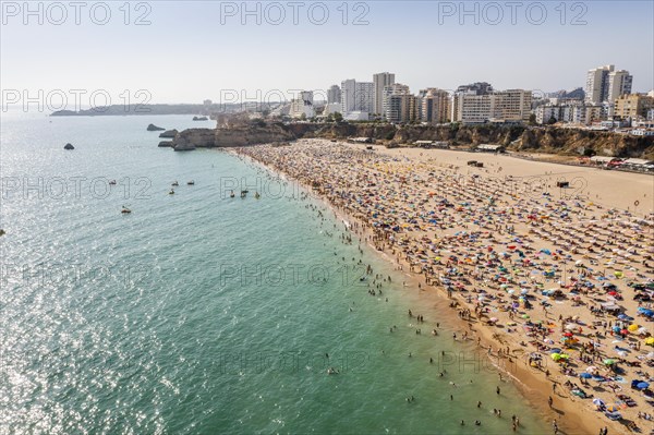 Aerial view of touristic Portimao with wide sandy beach Rocha full of people