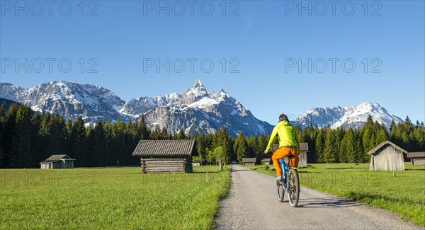 Mountain biker on road through meadow with hay barns