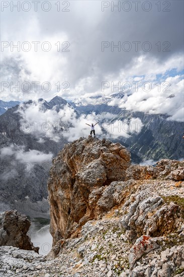 Hiker on a rock stretches arms in the air