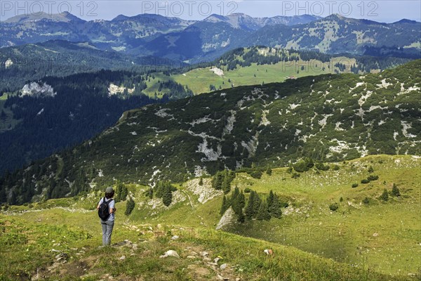 Hiker looking north from the hiking trail Obere Gottesackerwaende towards the Allgaeu Alps