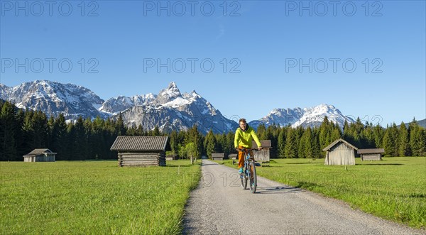 Mountain biker on road through meadow with hay barns